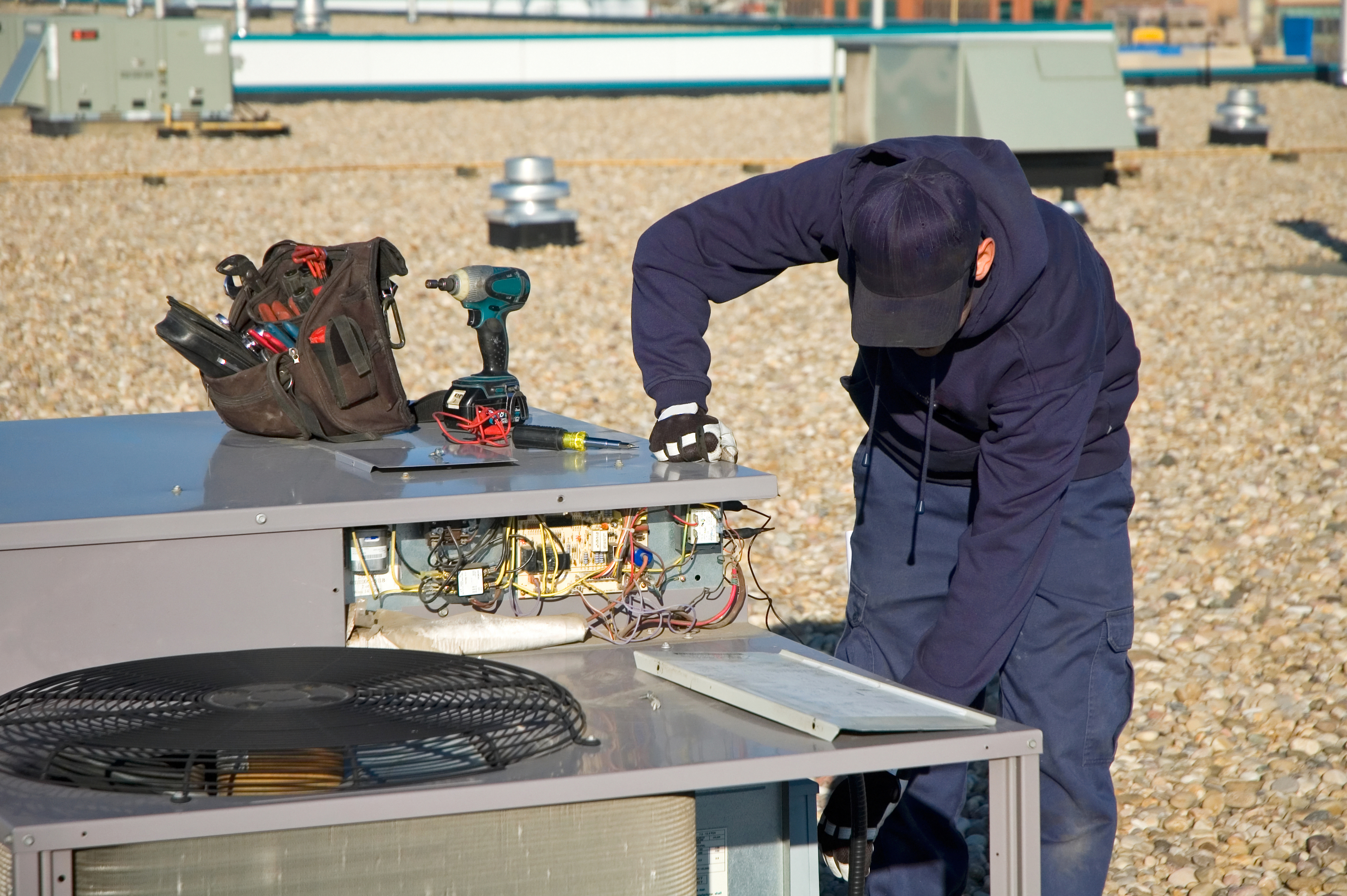 Image of a technician servicing a commercial HVAC rooftop unit in Saskatoon