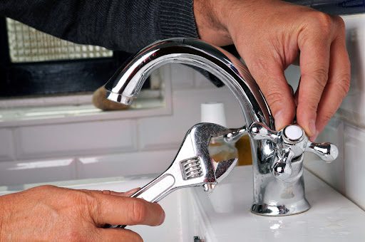 Man using a wrench to repair a bathroom faucet - fixing a leaky faucet.
